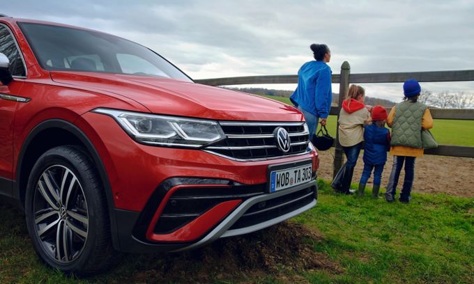 A family group standing next to a Tiguan Allspace farm fence